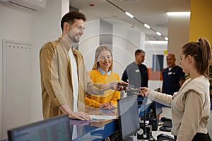 Young couple paying for doctor appointment at clinic reception using smartphone