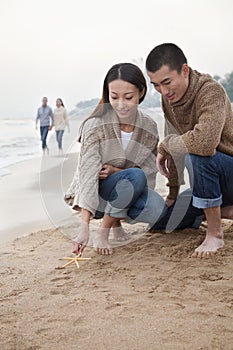 Young Couple Picking Up Starfish on the Beach