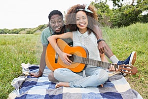 Young couple on a picnic playing guitar