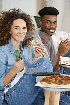 young couple with pizza and tv remote