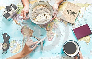 Young couple planning world tour with travel map while doing breakfast - Backpackers people looking for a new countries to explore