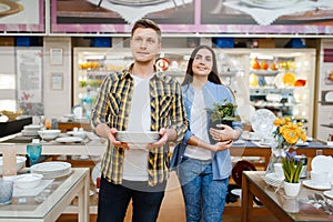 Young couple with plates in houseware store