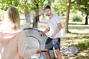 Young couple playing badminton by their tent photo