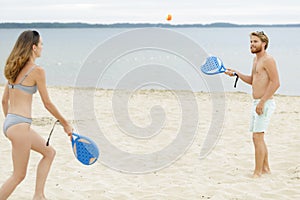 Young couple playing beach tennis