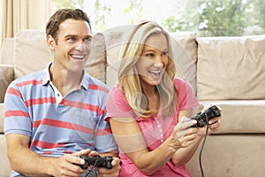 Young Couple Playing Computer Game On Sofa At Home
