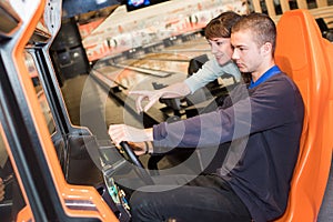 young couple playing driving wheel video game in game room