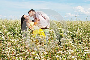 Young couple playing on field of flowers in sunny