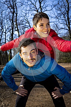 Young couple is playing happy in the woods during a workout.