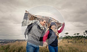 Young couple playing outdoors with blanket in a