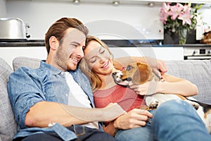 Young Couple Playing With Pet Dog At Home