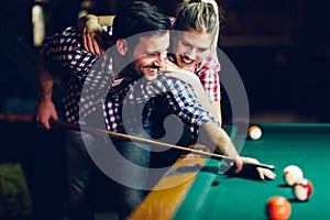 Young couple playing snooker together in bar