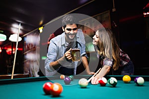 Young couple playing snooker together in bar