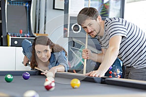 young couple playing snooker together in bar