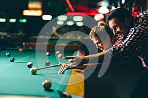 Young couple playing snooker together in bar