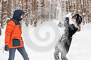 Young couple playing in snow, having snowball fight