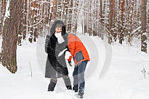 Young couple playing in snow, having snowball fight