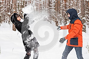 Young couple playing in snow, having snowball fight