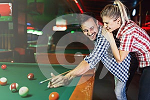 Young couple playing together pool in bar