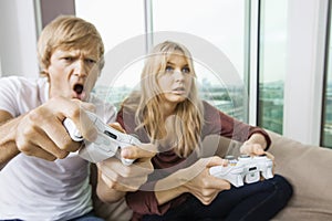 Young couple playing video game in living room at home