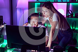 Young couple playing video games celebrating crazy and amazed for success with open eyes screaming excited