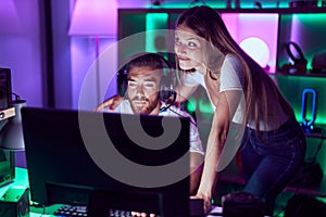 Young couple playing video games smiling looking to the side and staring away thinking