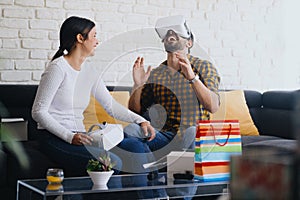 Young Couple Playing Virtual Reality With Headset On Sofa