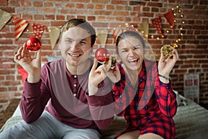 The young couple plays Christmas tree decorations.