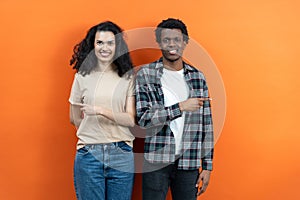 Young Couple Pointing Sideways On Orange Background