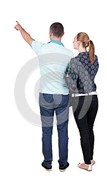 Young couple pointing at wal Back view
