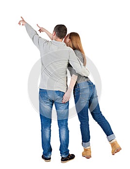 Young couple pointing at wal Back view (woman and man).