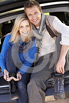 Young couple pose together at rear of car