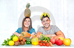 Young couple posing at home kitchen with healthy vegetarian food and fruit - Love concept about positive people