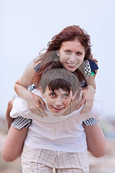 Young couple posing piggyback outdoors in overcast day