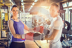 Young couple posing with red boxing gloves at the gym.