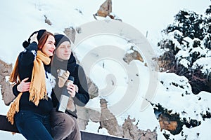 Young couple pours hot tea out of thermos in winter forest