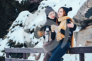 Young couple pours hot tea out of thermos in winter forest