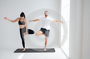 Young couple practicing yoga in a white room