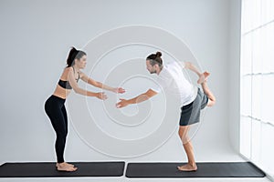 Young couple practicing yoga in a white room