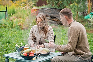 A young couple is preparing for a family barbecue dinner in the courtyard of the house. Cut vegetables on the picnic