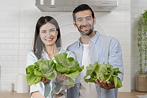 Young couple preparing food, holding vegetables in the kitchen at home. Healthy lifestyle of newlyweds, cooking at home
