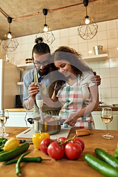 Young couple preparing a meal together in the kitchen, Italian man, chef cook helping his girlfriend to use hand blender