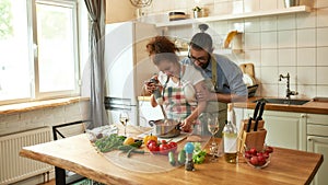 Young couple preparing a meal together in the kitchen. Italian man, chef cook helping his girlfriend to use hand blender