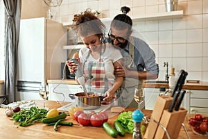 Young couple preparing a meal together in the kitchen. Italian man, chef cook helping his girlfriend to use hand blender