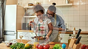 Young couple preparing a meal together in the kitchen. Italian man, chef cook helping his girlfriend to use hand blender