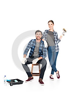 young couple in protective gloves with paint brush roller tray and paint roller