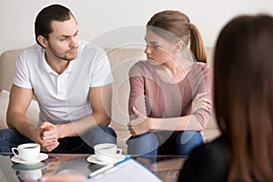 Young couple at psychologist, looking at each other with hate