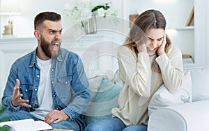 Young couple quarrelling, aggressive boyfriend yelling at sad lady