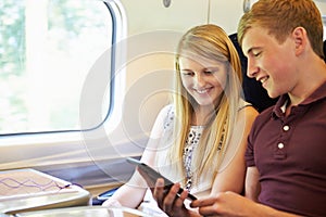 Young Couple Reading A Book On Train Journey