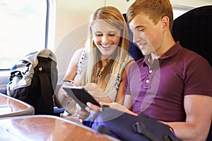 Young Couple Reading A Book On Train Journey