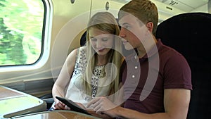 Young Couple Reading E Book On Train Journey